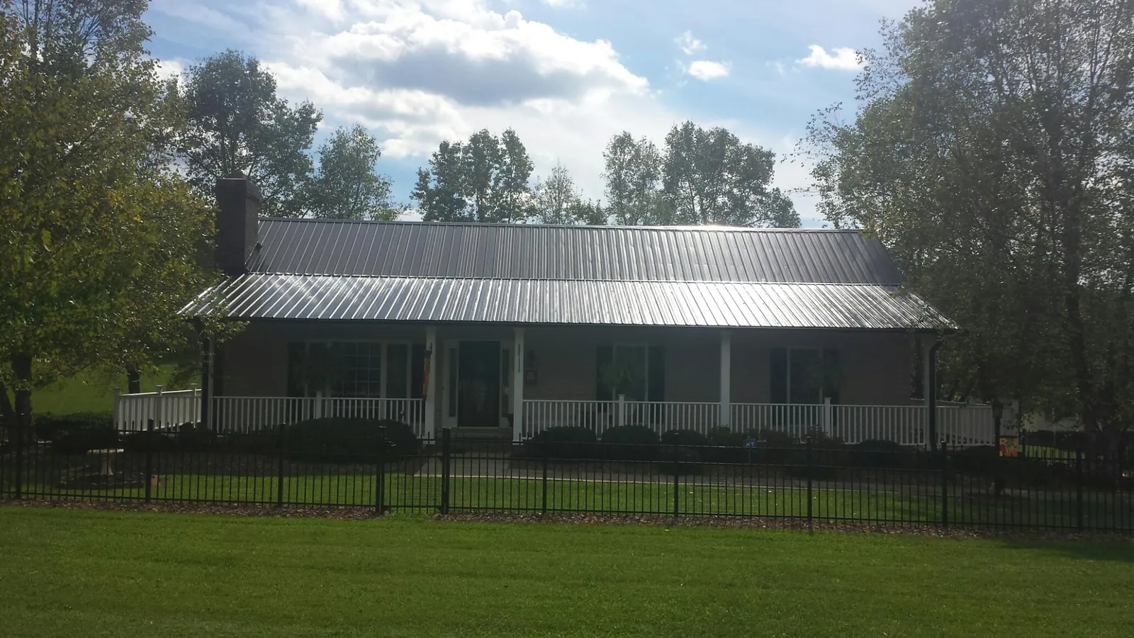 Gray metal roof on a brick ranch with a full width front porch — Gutter Guard Installation work by our crew in Glide