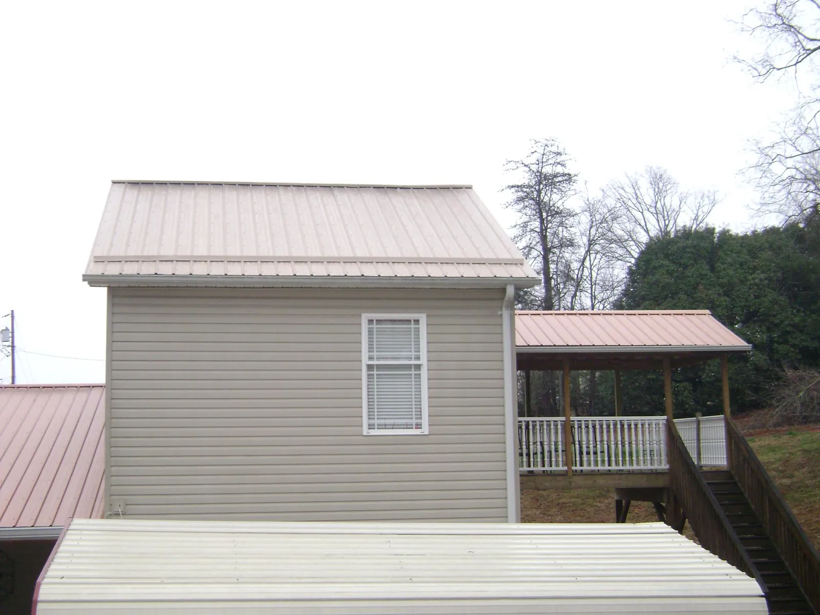 Tan metal roofs on a two story addition and attached porch, from a Roof Replacement job in Glide