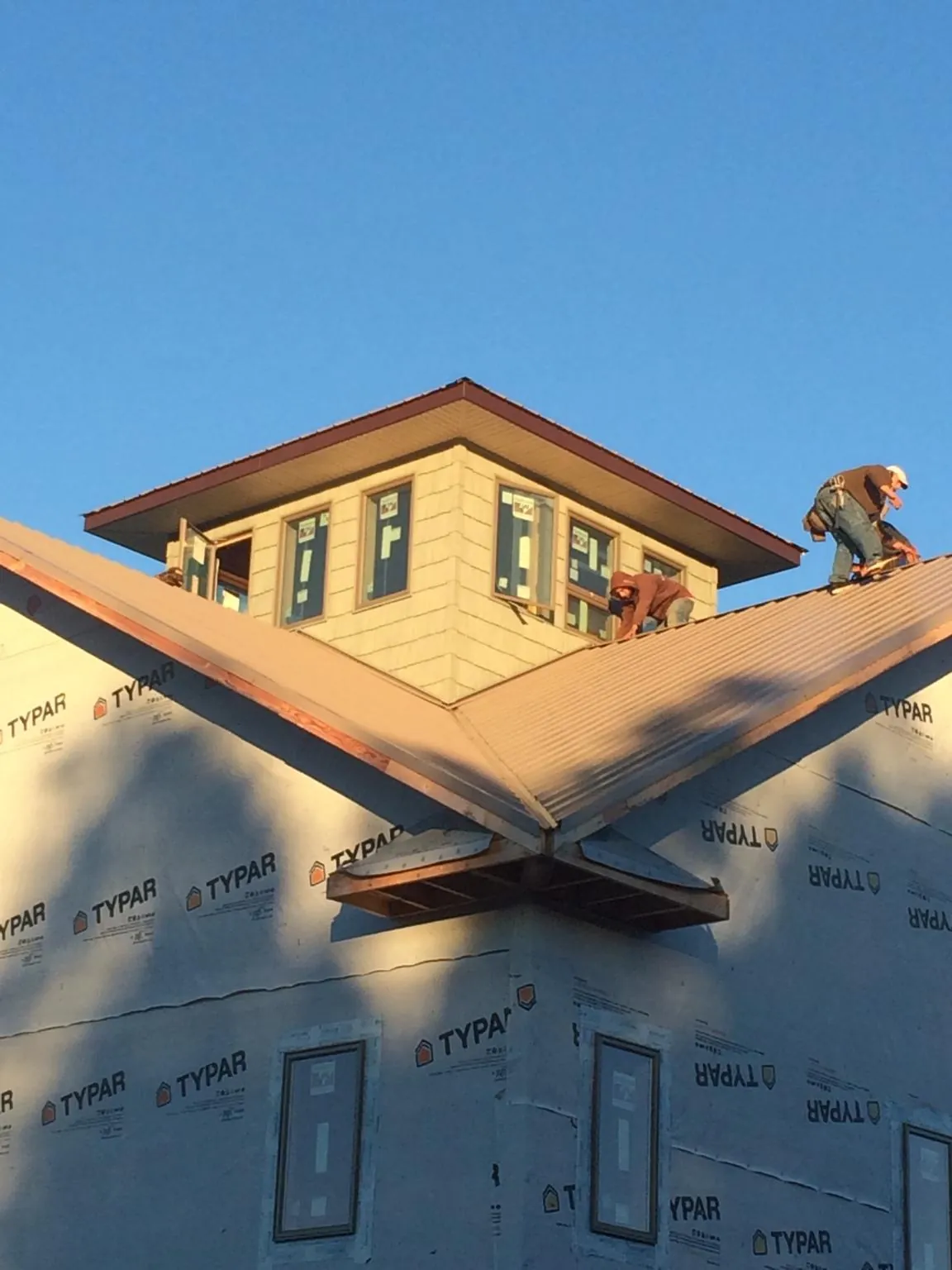 Roofers working around a rooftop cupola on a new metal roof at sunset — Roof Waterproofing in Glide by Roofing Brothers